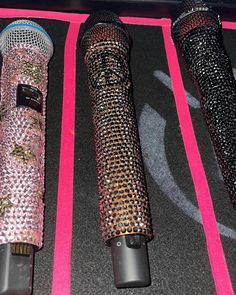 three microphones sitting on top of a black floor next to each other in front of a pink background