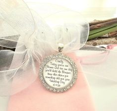 a necklace with a poem on it sitting on top of a piece of cloth next to some flowers