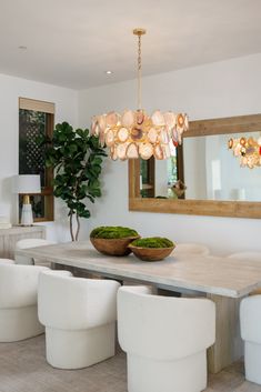 a dining room table with white chairs and a large mirror on the wall above it