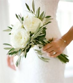 a bride holding a bouquet of white flowers