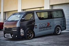 a silver van parked in front of a building next to a red car with the word mrx on it's side