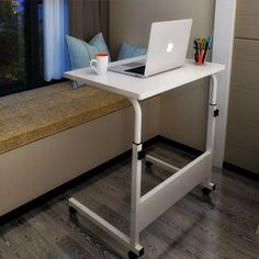 a laptop computer sitting on top of a white desk next to a window sill