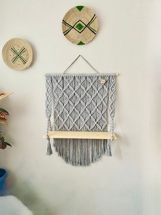 three woven wall hangings are hung on the wall next to a potted plant