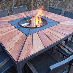 a wooden table with chairs around it and a fire pit on top of the table