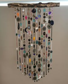 a wall hanging made out of beads and other items with a wooden stick attached to it