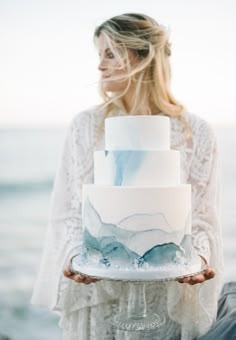 a woman holding a white and blue wedding cake