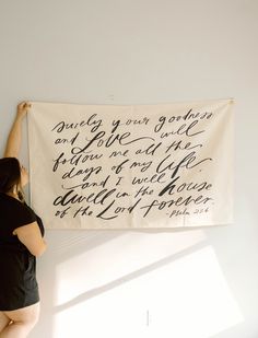 a woman standing next to a wall hanging a banner