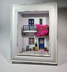 a miniature house with pink flowers in the window and balconies on the balcony