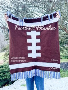 a person holding up a football blanket in front of a tree with the words football blanket written on it