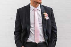 a man in a suit and pink tie with a boutonniere on his lapel