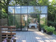 a glass house sitting on top of a wooden deck