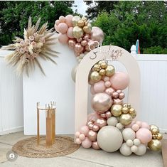 a large balloon arch is decorated with pink, gold and white balloons