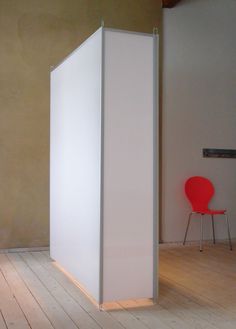 a room divider in the middle of a wooden floor with a red chair next to it