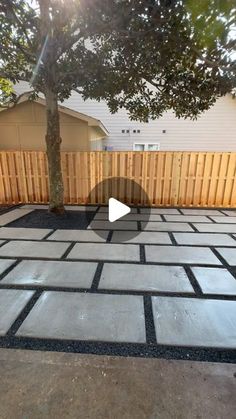 an outdoor patio being built in front of a house with a tree and fence behind it