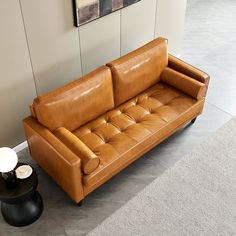 a brown leather couch sitting on top of a gray floor next to a black table