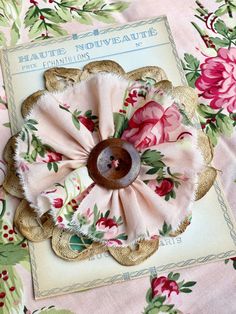 a pink flower with green leaves and red flowers on a floral fabric covered table cloth