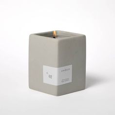 a candle that is sitting on top of a white surface with a tag around it