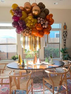 a dining room table with chairs and balloons hanging from it's ceiling in front of a window