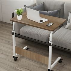 a laptop computer sitting on top of a wooden table next to a couch with wheels