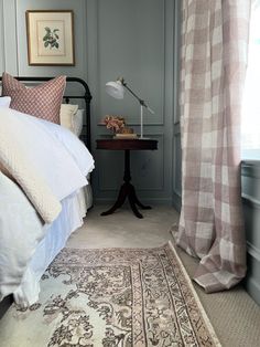 a bed sitting in a bedroom next to a window with curtains on the windowsill