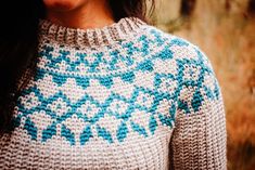 a close up of a woman wearing a sweater with blue and white designs on it