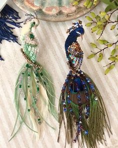 two peacocks are sitting on a plate with green and blue feathers hanging from it