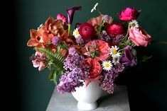 a white vase filled with lots of colorful flowers