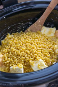 a wooden spoon in a crock pot filled with macaroni and cheese