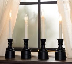 three candles sitting on top of a table next to a window