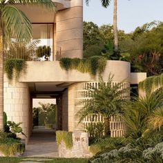 an entrance to a house surrounded by palm trees and greenery in front of it