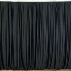 an empty room with black drapes on the wall