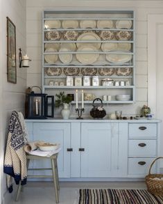 a kitchen with white cabinets and dishes on the shelves