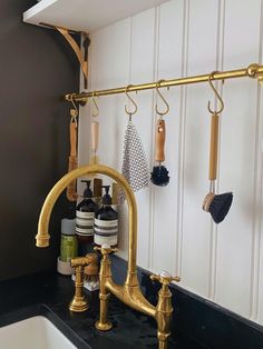 a kitchen sink with gold faucet and soap dispenser on the wall