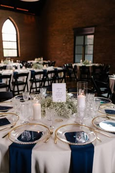 the table is set with blue and white linens, silverware, and candles