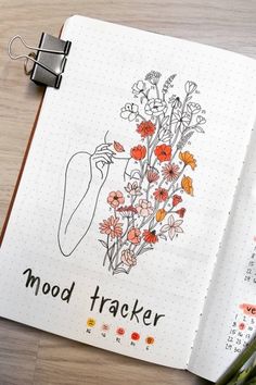 an open notebook with flowers on it and the words mood tracker written in black ink