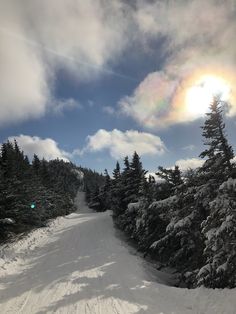 the sun shines brightly through the clouds above trees on a snow covered mountain slope