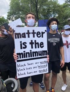 some people are holding signs and wearing masks