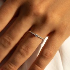 a woman's hand with a diamond ring on top of her finger and the bottom half of her wedding band