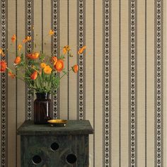 a vase with flowers sitting on top of a wooden table next to a wallpaper