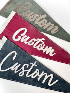 three pennants with the words custom on them, one is red and one is green