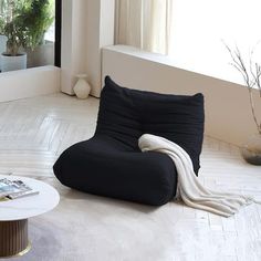 a black bean bag chair sitting on top of a floor next to a white coffee table