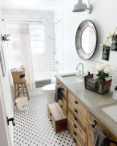 a bathroom with black and white tile flooring, wooden cabinets and vanity mirror above the sink