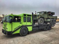 a large green truck parked on top of a dirt field