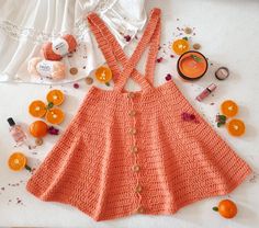 an orange crocheted dress and other items are laid out on the table next to it