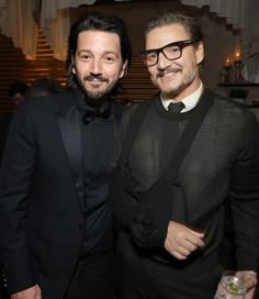 two men standing next to each other in formal wear and tuxedos at an event