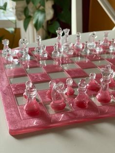 a pink chess board with glass figures on it