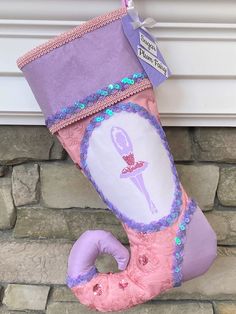 a pink and purple stocking with a ballerina on it hanging from a brick wall