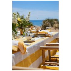 the table is set with yellow and white striped cloths, plates and glasses on it