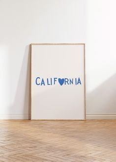 a white framed poster with the word california in blue on it against a white wall