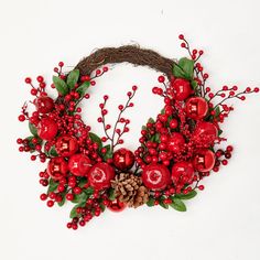 a wreath with red berries and pine cones